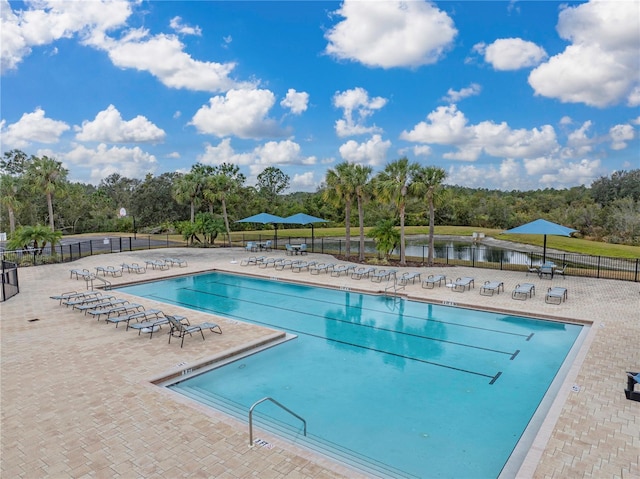 view of swimming pool featuring a water view and a patio