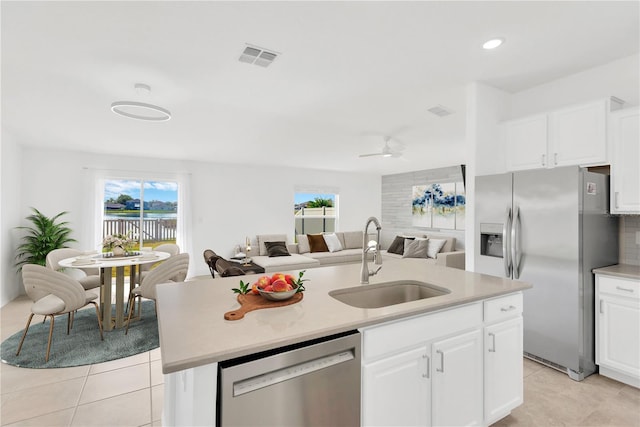 kitchen with sink, stainless steel appliances, an island with sink, white cabinets, and light tile patterned flooring