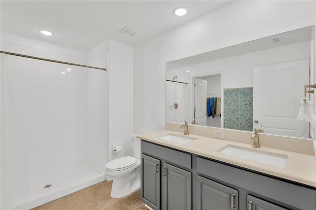 bathroom with vanity, tile patterned floors, toilet, and tiled shower