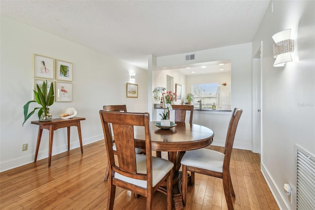 dining room with a textured ceiling and light hardwood / wood-style flooring