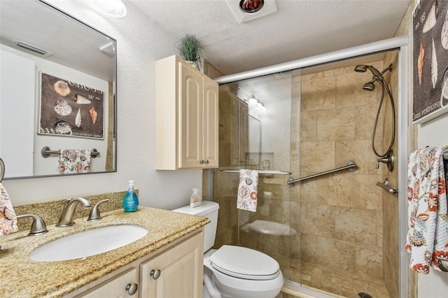 bathroom with vanity, a textured ceiling, a shower with shower door, and toilet