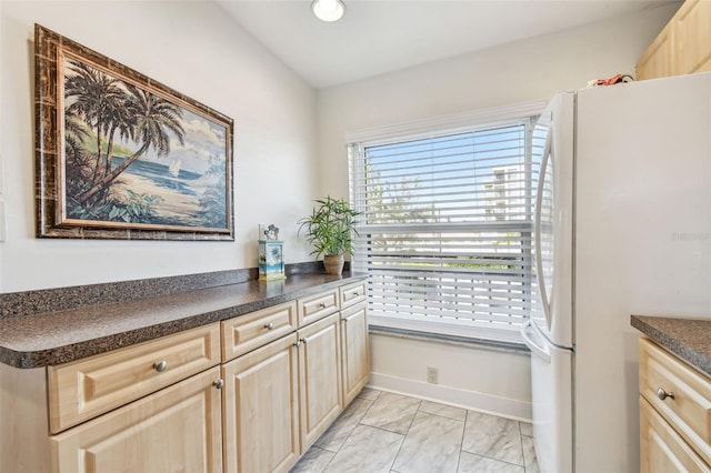 kitchen featuring white fridge and light brown cabinetry