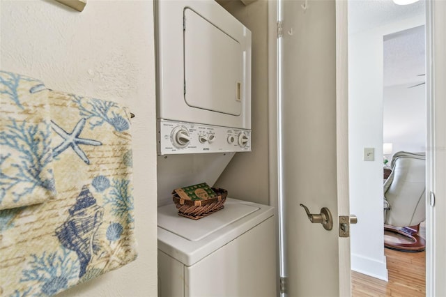 laundry area featuring stacked washer and dryer and hardwood / wood-style floors