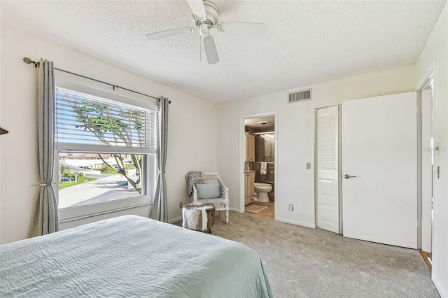 carpeted bedroom with ensuite bathroom, a textured ceiling, ceiling fan, and a closet