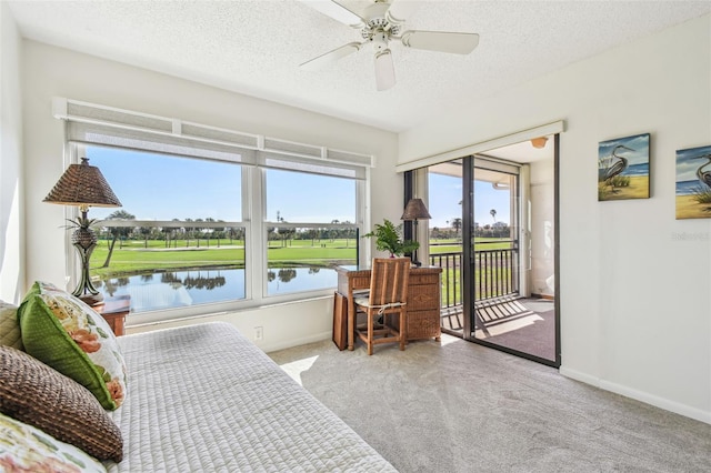 carpeted bedroom with a water view, ceiling fan, access to exterior, and a textured ceiling