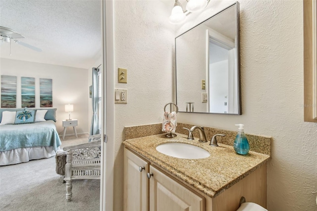 bathroom with vanity, ceiling fan, and a textured ceiling