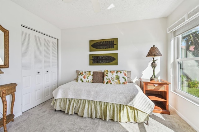 carpeted bedroom with ceiling fan, multiple windows, a closet, and a textured ceiling