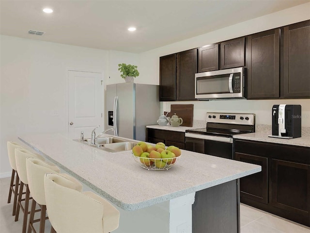 kitchen with a center island with sink, sink, appliances with stainless steel finishes, and a breakfast bar area