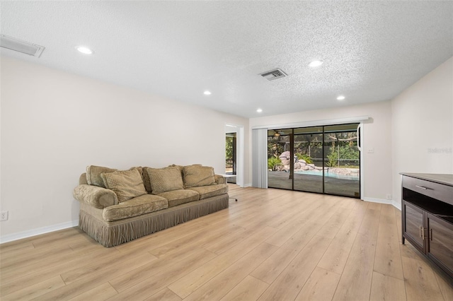 living room with light wood-type flooring and a textured ceiling