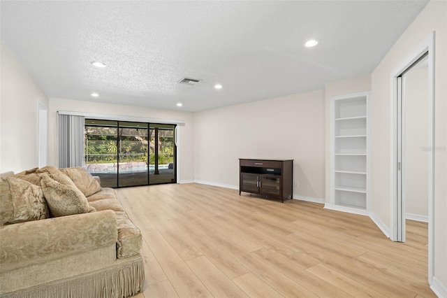 living room with a textured ceiling and light wood-type flooring