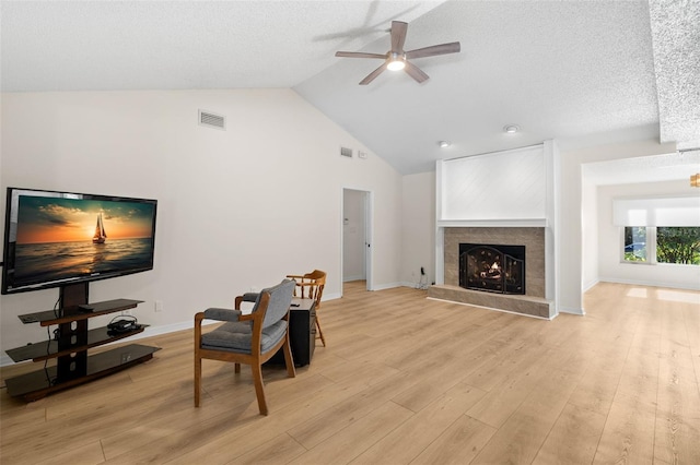 living room with ceiling fan, light wood-type flooring, a textured ceiling, and high vaulted ceiling