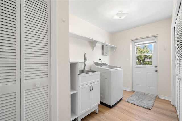 laundry area featuring cabinets, washer / dryer, light wood-type flooring, and sink