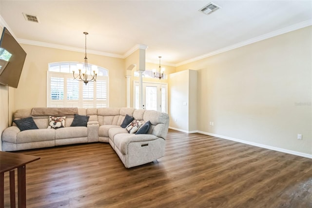 living room featuring decorative columns, ornamental molding, dark hardwood / wood-style floors, and a notable chandelier