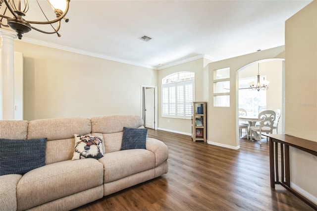 living room with ornate columns, ornamental molding, dark wood-type flooring, and an inviting chandelier