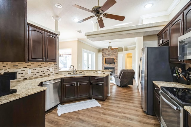 kitchen featuring dark brown cabinetry, sink, stainless steel appliances, crown molding, and light hardwood / wood-style floors