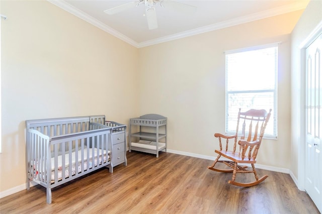 bedroom with hardwood / wood-style floors, a nursery area, and multiple windows