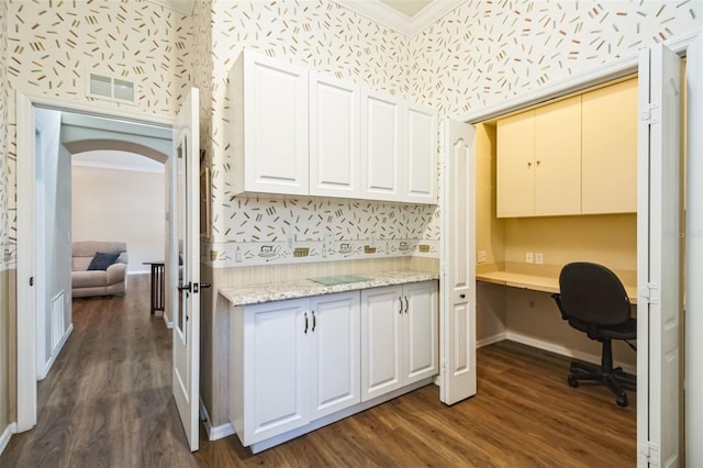 kitchen featuring white cabinets, built in desk, dark wood-type flooring, and crown molding