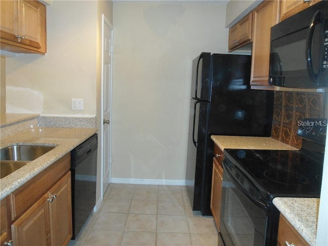 kitchen with light stone countertops, light tile patterned floors, and black appliances