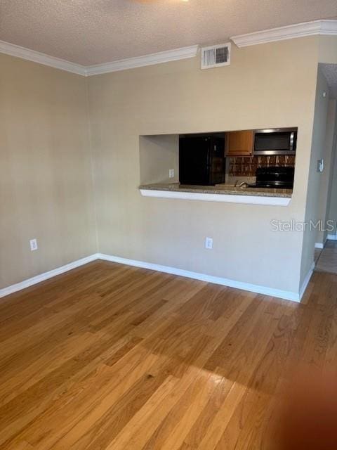 kitchen featuring kitchen peninsula, light wood-type flooring, a textured ceiling, black refrigerator, and ornamental molding