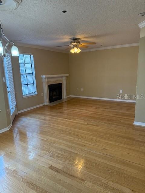 unfurnished living room with crown molding, light hardwood / wood-style floors, and a textured ceiling