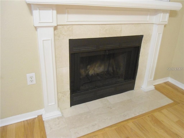 details featuring a tile fireplace and hardwood / wood-style floors