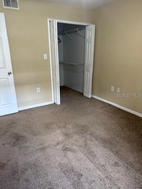 unfurnished bedroom with a closet, carpet, and a textured ceiling