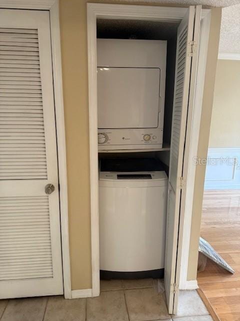 laundry room featuring stacked washer and dryer and light hardwood / wood-style floors