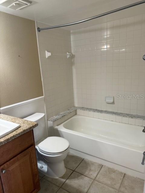 full bathroom with toilet, vanity, tile patterned floors, and tiled shower / bath combo