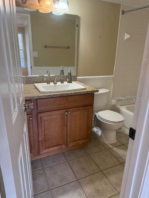 full bathroom featuring tile patterned flooring, vanity, toilet, and tiled shower / bath combo