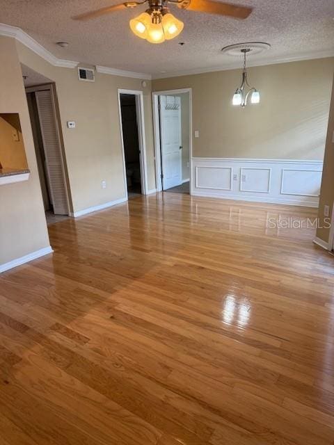 empty room with a textured ceiling, hardwood / wood-style flooring, and ornamental molding