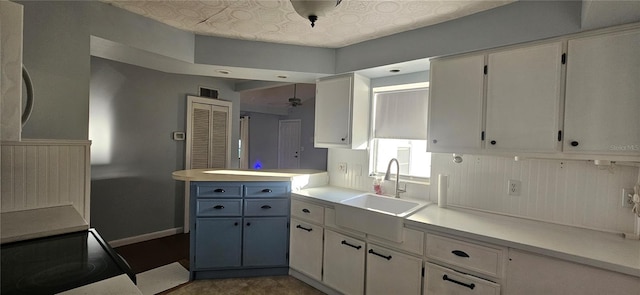 kitchen featuring decorative light fixtures, white cabinetry, ceiling fan, and sink