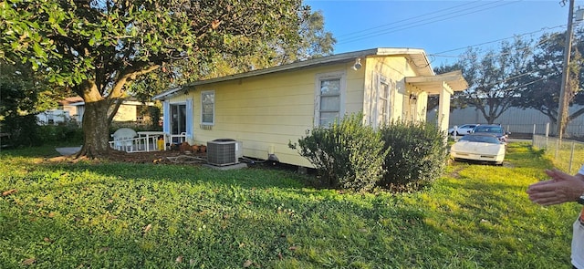 view of side of home featuring cooling unit and a lawn