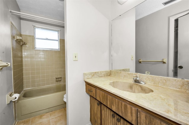 full bathroom featuring tiled shower / bath combo, tile patterned floors, a textured ceiling, toilet, and vanity