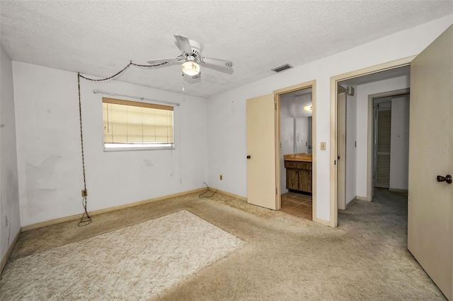 unfurnished bedroom featuring connected bathroom, ceiling fan, light carpet, and a textured ceiling