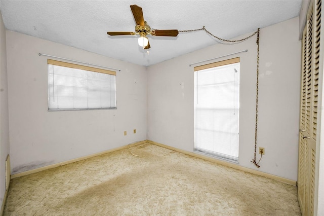 unfurnished room with a textured ceiling, carpet floors, and ceiling fan