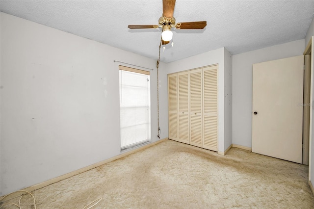 unfurnished bedroom with ceiling fan, light colored carpet, a textured ceiling, and a closet