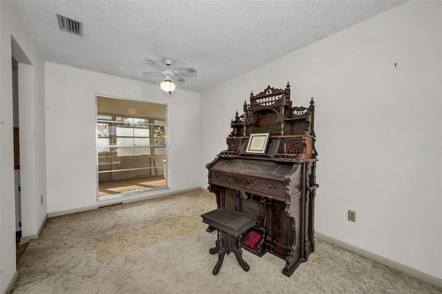 misc room with a textured ceiling, light colored carpet, and ceiling fan