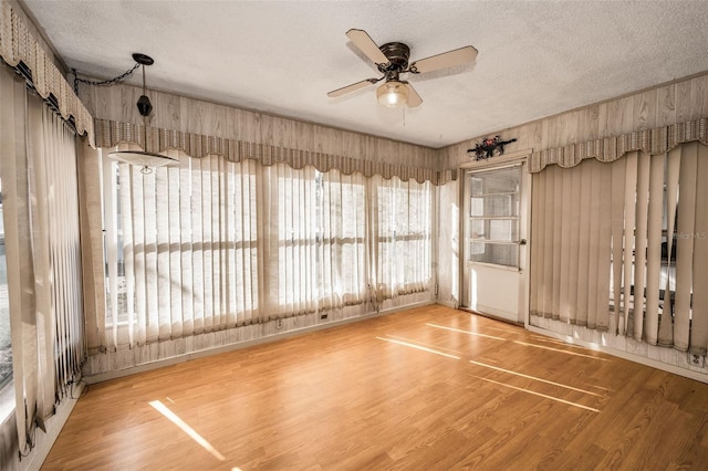 empty room with ceiling fan, wood-type flooring, and a textured ceiling