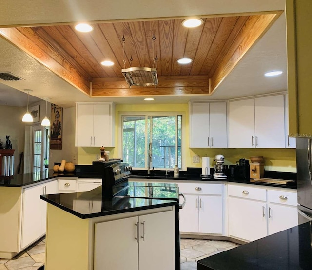 kitchen featuring white cabinets, decorative light fixtures, a center island, and a tray ceiling