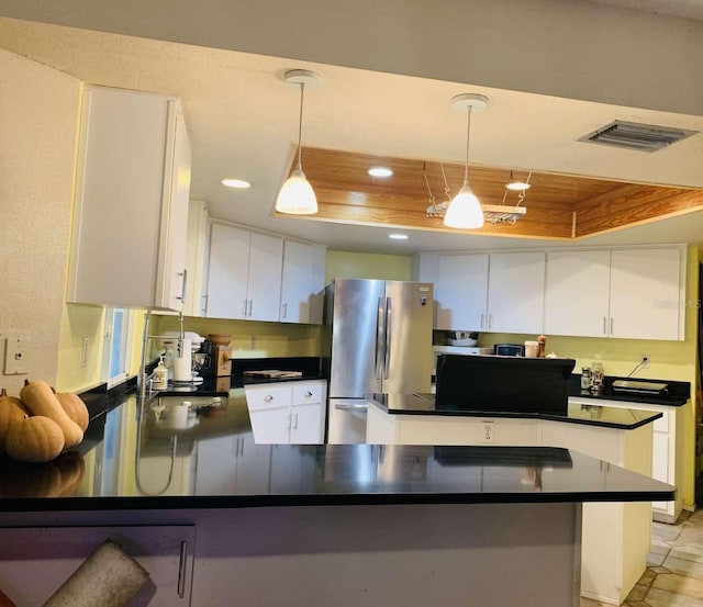 kitchen featuring decorative light fixtures, white cabinetry, kitchen peninsula, and stainless steel refrigerator