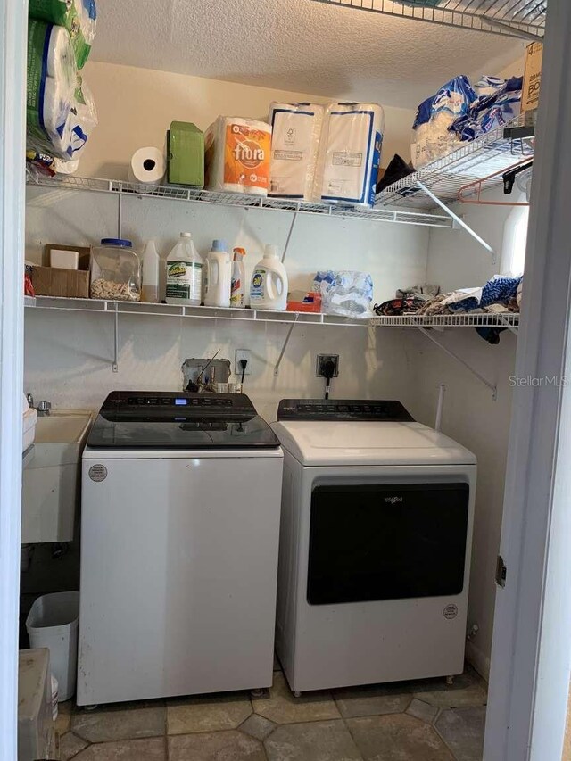 laundry area with separate washer and dryer, sink, and a textured ceiling