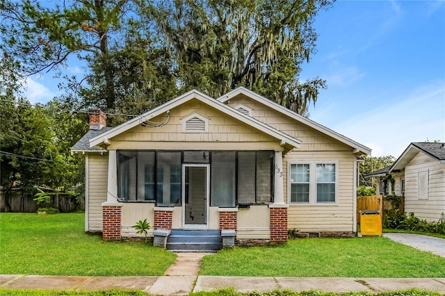 bungalow-style house featuring a front yard and a sunroom