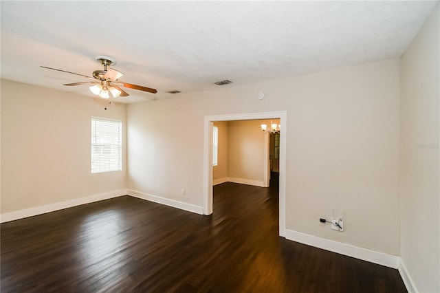 unfurnished room with ceiling fan with notable chandelier and dark hardwood / wood-style flooring