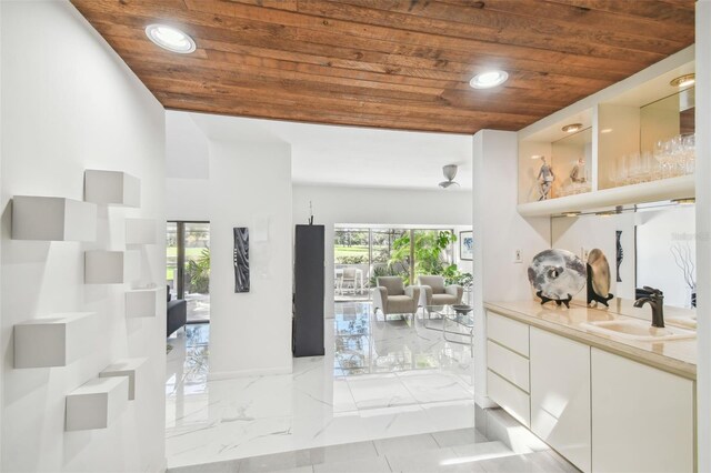 interior space with white cabinets, wooden ceiling, and sink