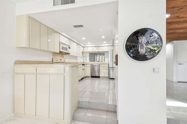 kitchen with sink, light tile patterned floors, and stainless steel appliances