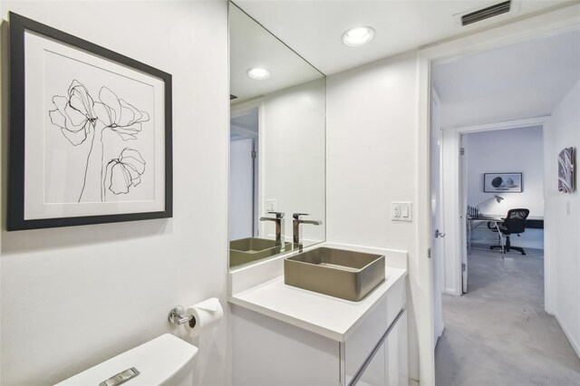 bathroom featuring sink, concrete flooring, and toilet