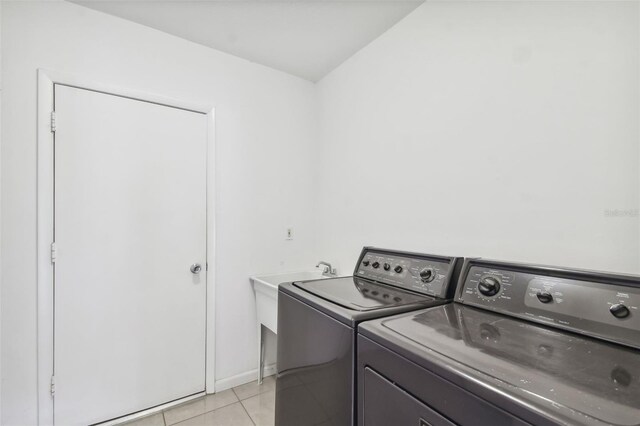 clothes washing area featuring washer and clothes dryer and light tile patterned floors