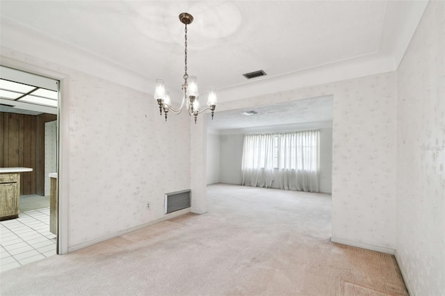 carpeted spare room featuring a chandelier