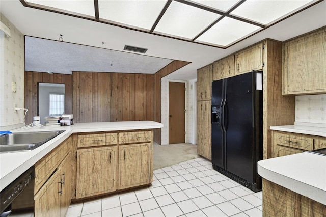 kitchen with kitchen peninsula, wooden walls, light tile patterned floors, and black appliances