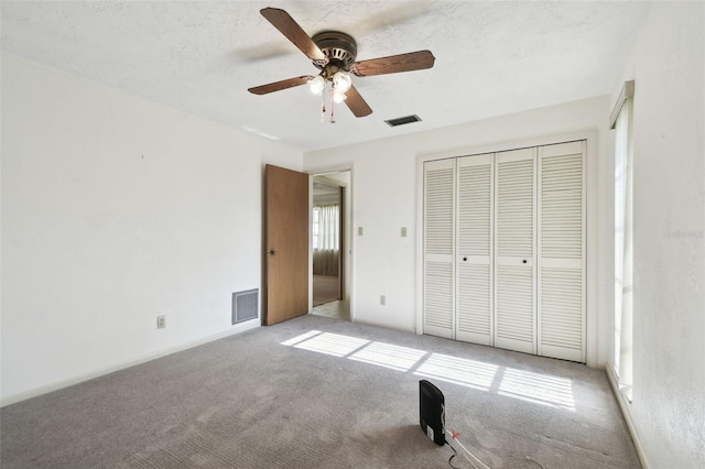 unfurnished bedroom featuring a textured ceiling, ceiling fan, light carpet, and a closet